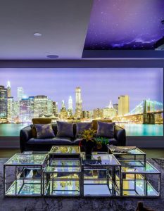 Modern basement renovation in Toronto with illuminated city skyline wall mural, mirrored coffee table, and plush seating under a starry ceiling