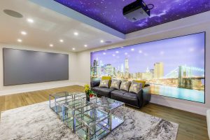 Spacious and modern basement finishing in Toronto with large screen projector, night sky ceiling mural, and cityscape wall art.